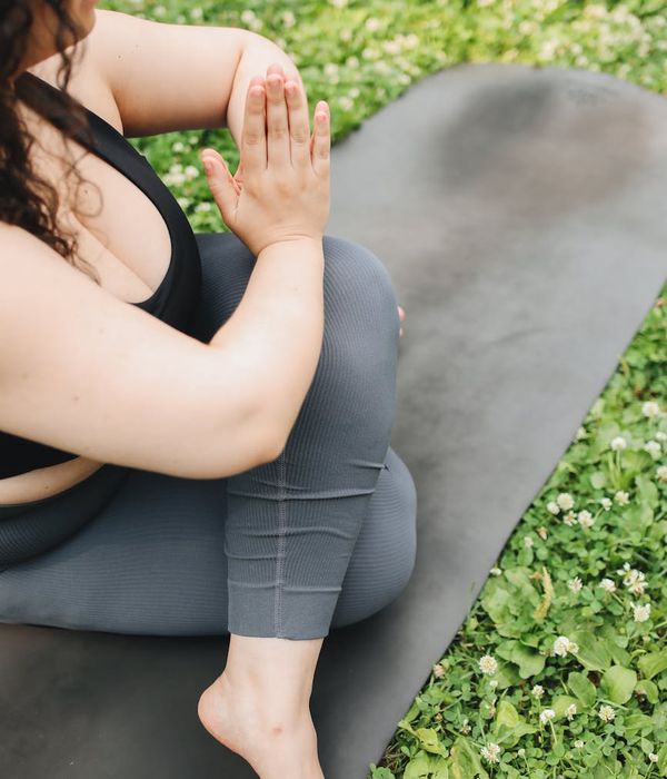 Person in a mindful yoga pose on a light green background.